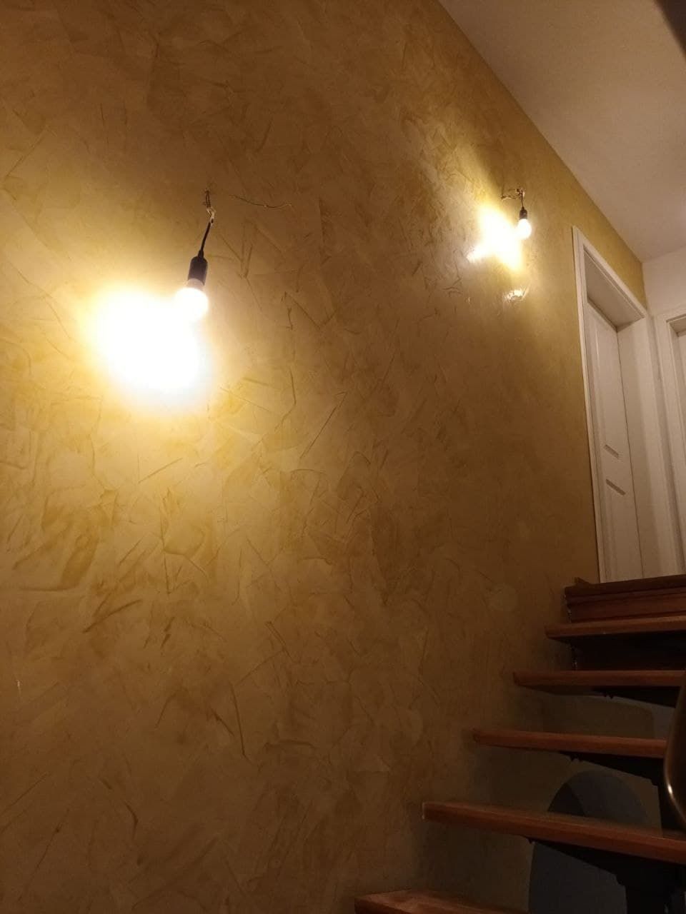 Treppenhauswand mit warmer, mehrschichtiger Lasur, daneben eine weiße Türzarge mit sauberem Anschluss.